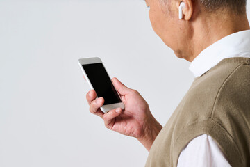 スマートフォンを使う私服姿のシニア男性の後ろ姿