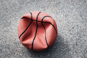 a deflated basketball. business, economy, sports, life, or potential metaphor design element. looking down at aerial view.  isolated on a concrete background. top down aerial view.