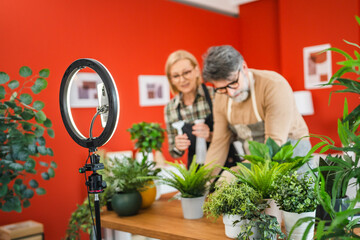 mature couple use cellphone for live streaming and presenting home plants