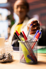 Woman in home office reaching for pencil from desk organizer, preparing to jot down important...