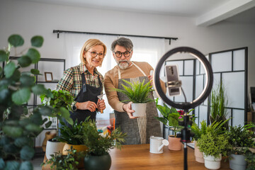 mature couple use cellphone for live streaming and presenting home plants