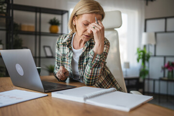 Mature tired woman work from home and have eyestrain pain busy day
