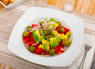 Fresh salad with avocado, tomato, olives and onion at plate