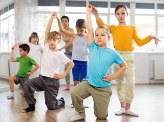 Positive juvenile boy and girl doing ballroom dance in pair in training room during workout session