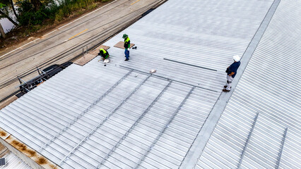 A sustainable energy project featuring solar panels on a roof surrounded by tropical trees,...