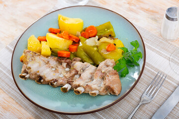 Portion of just cooked ribs with potato and other vegetables served on table.