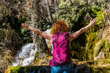 Hiker feeling free with open arms in front of waterfall during hiking trip