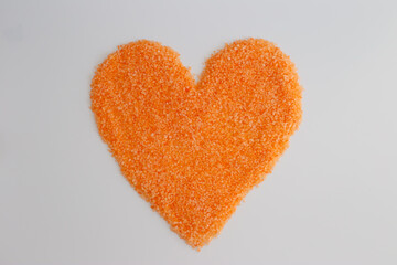 Heart shape created with sea salt in vibrant orange color arranged on clean surface
