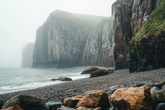 Misty coastal cliffs, dark pebble beach, dramatic ocean waves