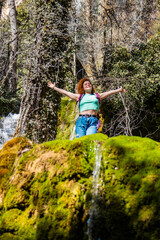 Fototapeta premium Tourist enjoying freedom in wild nature with open arms near waterfall