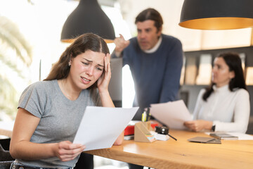 Upset manager woman with documents against the background of emotional customers, she listens to the man's dissatisfaction with the delivery time