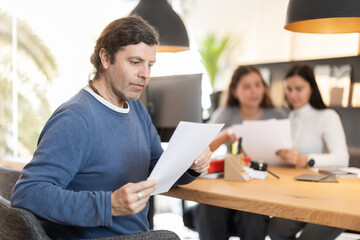 Adult man carefully reads the terms of the contract in a furniture store