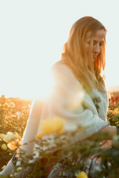 Closeup of woman in field of yellow roses