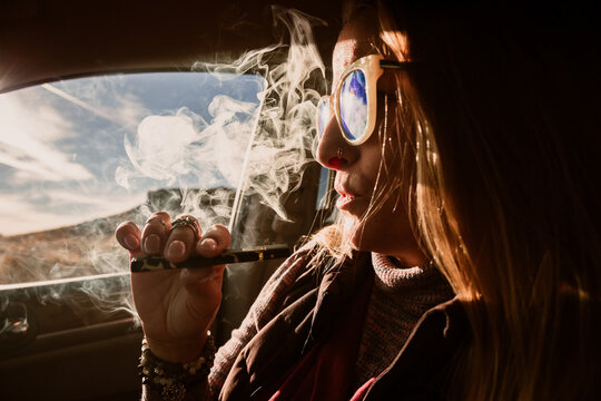 Woman smoking in car with sunglasses
