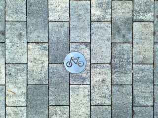 Bicycle Sign Embedded in Grey Cobblestone Pavement