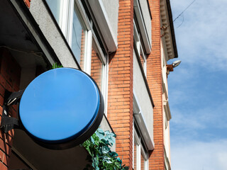 Empty round blue sign mounted on storefront in Riga, Latvia, suitable for advertising, branding, or...