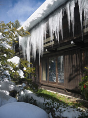 Big icicles hanging from the rooftop on blue sky background