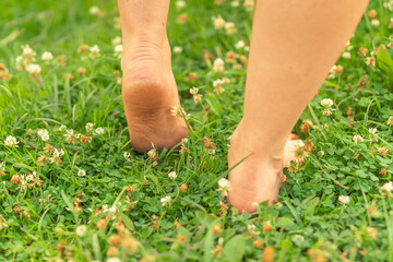 Close-up of heels lifting from a grassy field with small wildflowers.