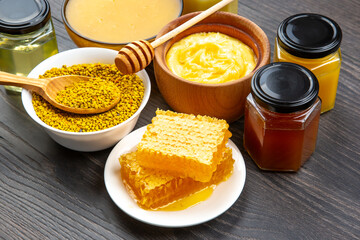 Fresh flower honey of different varieties, pollen and honeycomb with spoons on a wooden background....