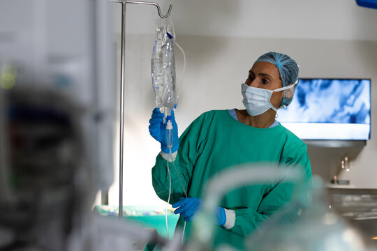 Medical professional adjusting IV drip in hospital operating room, focused on task, copy space