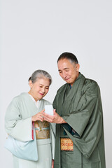 Fototapeta premium 一緒にスマートフォンを使う着物を着たシニア夫婦