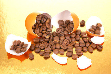 A cracked orange egg spills coffee beans onto a reflective gold surface, surrounded by broken...