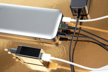 Power bank and charging plug on a golden background. Electronic devices for charging gadgets