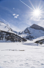 Fototapeta premium People walking across winter mountain landscape on a sunny day