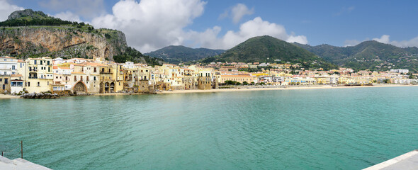 Panoramic photo of Cefalu a village and comune in the Italian Metropolitan City of Palermo, located on the Tyrrhenian coast of Sicily with La Rocca rock and Madonie Mountains in the background.