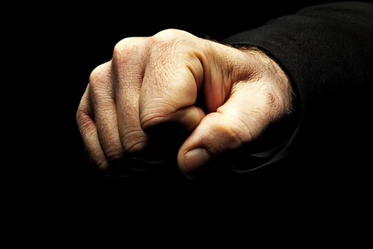 Hand clenched fist pointing forward, dark background