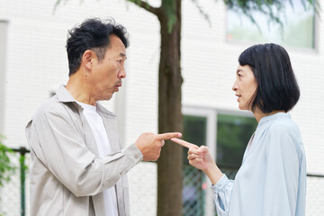 夫婦喧嘩する中年の夫婦　屋外