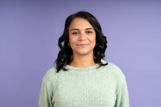 Confident latin woman smiling on purple background