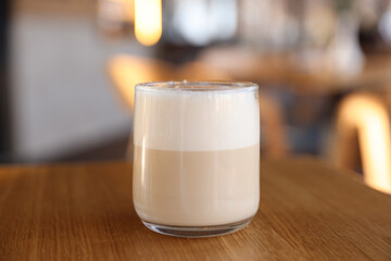 Glass of aromatic coffee on wooden table in cafe, closeup