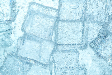 Refreshing soda water with ice cubes as background, closeup