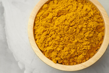 Turmeric powder in bowl on light grey table, top view