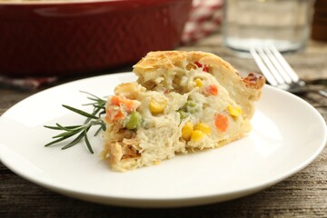 Piece of tasty homemade pie with chicken and vegetables on wooden table, closeup