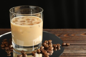 Coffee cream liqueur in glass and beans on wooden table, closeup. Space for text