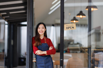 Asian Happy business woman is a waitress in an apron and stands at the door with a sign Open waiting for customers , cafes and restaurants Small business concept.
