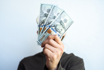 Unidentified woman holding various of American dollar banknotes against white wall.