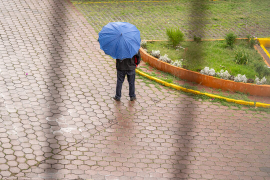 un hombre con paraguas azul parado en lluvia ligera