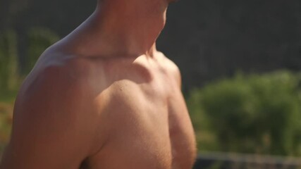 Side view close up. A sun kissed, handsome runner shirtless in sunglasses jogs against a picturesque sunset backdrop. The light gently illuminates his face, reflecting his endurance and determination.