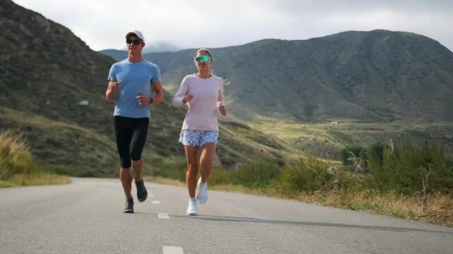 A couple trains for a trail running championship, jogging along a mountainous road. Their steady pace and focused expressions show determination as they prepare for the competition.