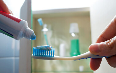 Cepillo y pasta de dientes con artículos de cuidado oral en botiquín o tocador de baño al fondo. 