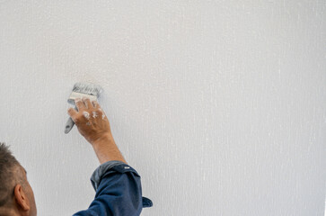 mano de hombre pintando pared blanca con espacio para texto