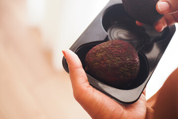 Picking ripe avocados from a plastic container in a kitchen