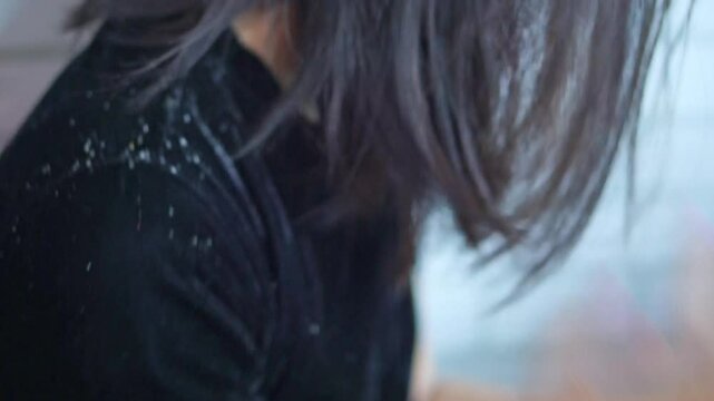 woman with irritated scalp, scratching due to dandruff and excessive flakes on her hair and shoulders from skin conditions, dryness or chemical hair products