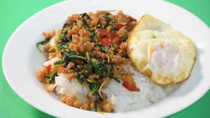 stir fried pork with holy basil on top with fried egg on cooked rice