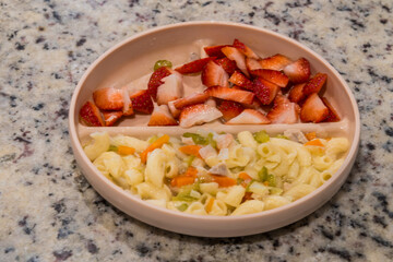 Healthy meal with pasta and fresh strawberries on a beige plate