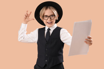 Little actor with film script on beige background