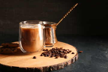 Glass cup of iced latte with coffee beans and cezve on black background